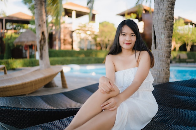 De jonge Aziatische vrouw ontspant dichtbij zwembad in hotel, Mooie vrouwelijke gelukkig ontspant dichtbij overzees.