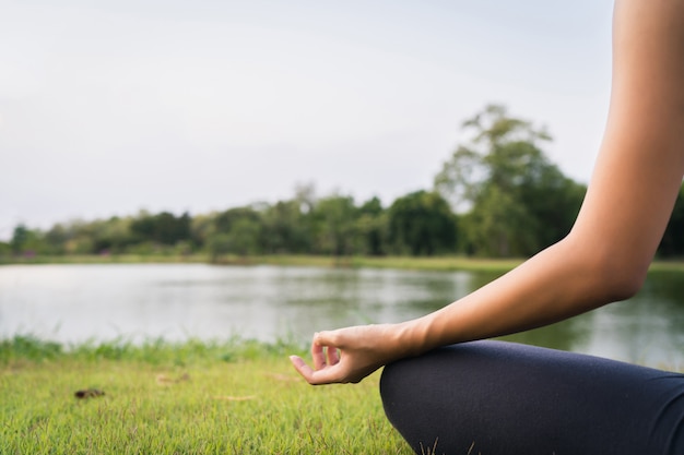 De jonge Aziatische vrouwenyoga houdt in openlucht kalm en mediteert terwijl het praktizeren van yoga