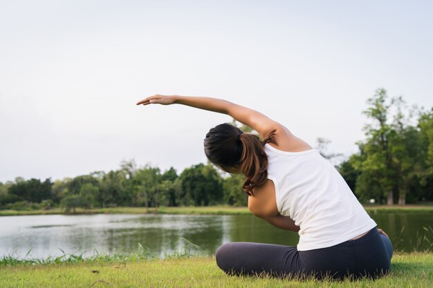 De jonge Aziatische vrouwenyoga houdt in openlucht kalm en mediteert terwijl het praktizeren van yoga