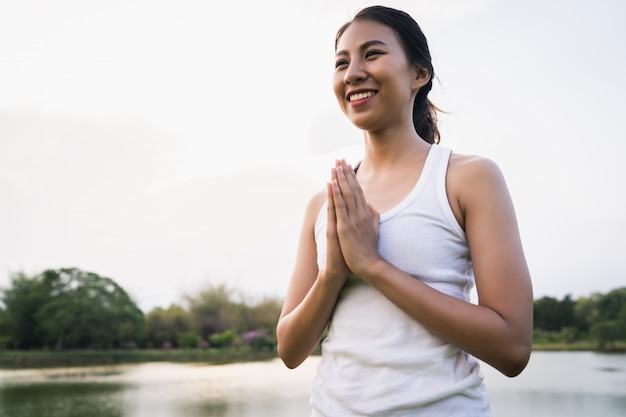 De jonge Aziatische vrouwenyoga houdt in openlucht kalm en mediteert terwijl het praktizeren van yoga