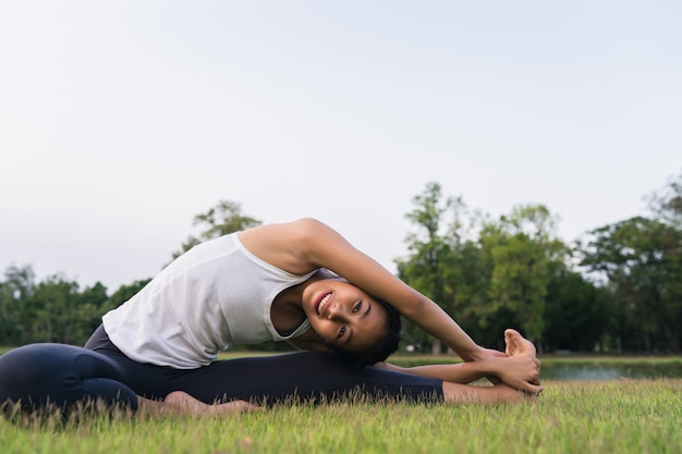 De jonge Aziatische vrouwenyoga houdt in openlucht kalm en mediteert terwijl het praktizeren van yoga