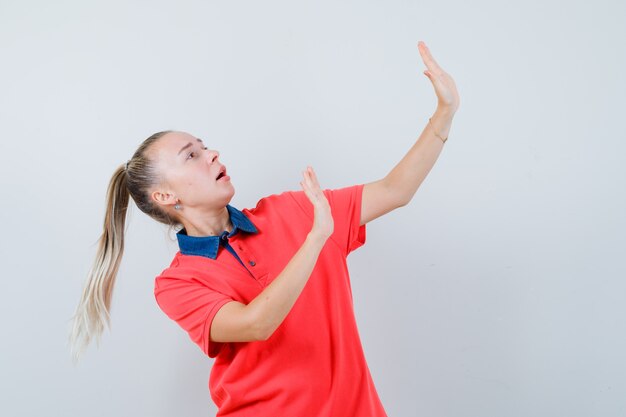 De jonge dame die dient op preventieve wijze in t-shirt op en kijkt bang