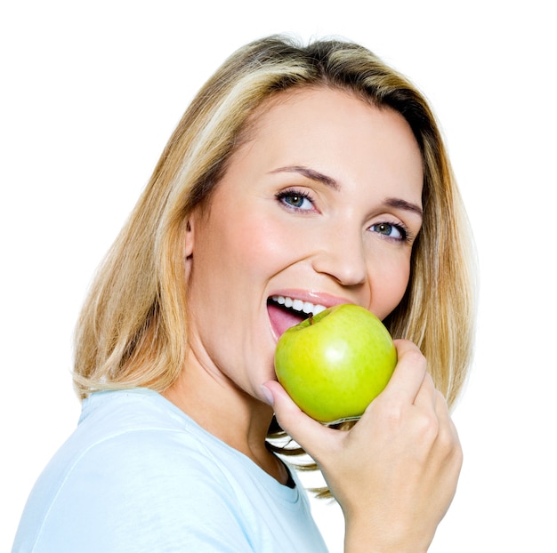 De jonge gelukkige vrouw eet groene appel