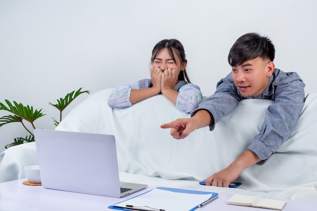 De jonge jongen en het meisje gebruiken labtop en genieten samen van de tijd behide bank thuis.