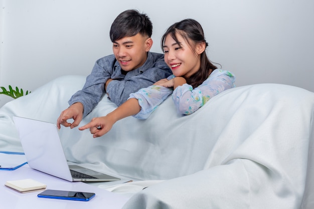 De jonge jongen en het meisje gebruiken labtop en genieten samen van de tijd behide bank thuis.