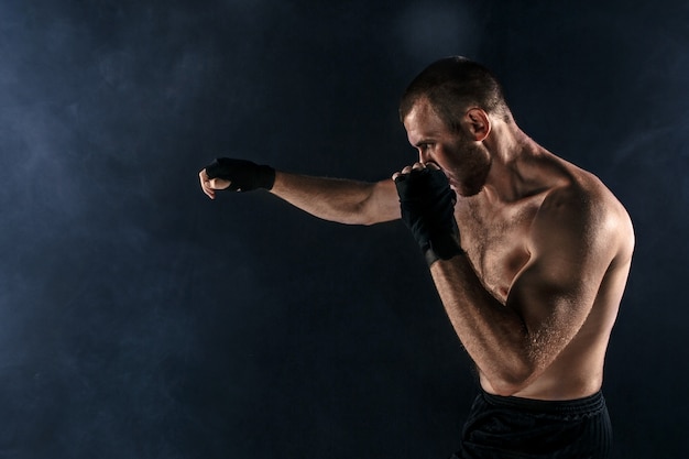 De jonge man die op zwarte copyspace kickboxing