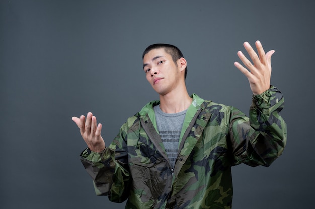 Gratis foto de jonge man draagt een camouflageregenjas en toont verschillende gebaren.