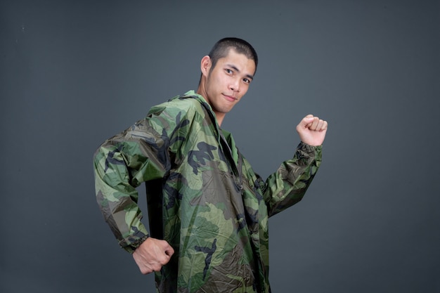 De jonge man draagt een camouflageregenjas en toont verschillende gebaren.