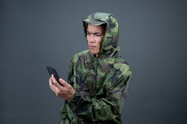 Gratis foto de jonge man draagt een camouflageregenjas en toont verschillende gebaren.