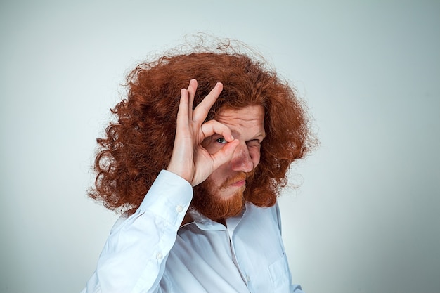 Gratis foto de jonge man met lang rood haar die naar de camera kijkt en zijn ogen verknalt