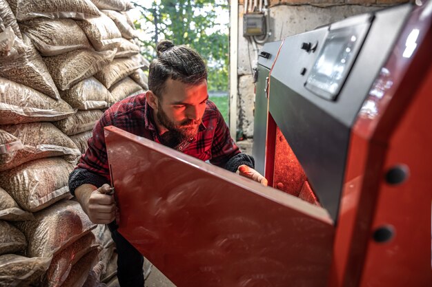 De jonge man op zoek naar een ketel voor vaste brandstoffen, werken met biobrandstoffen, zuinige verwarming.