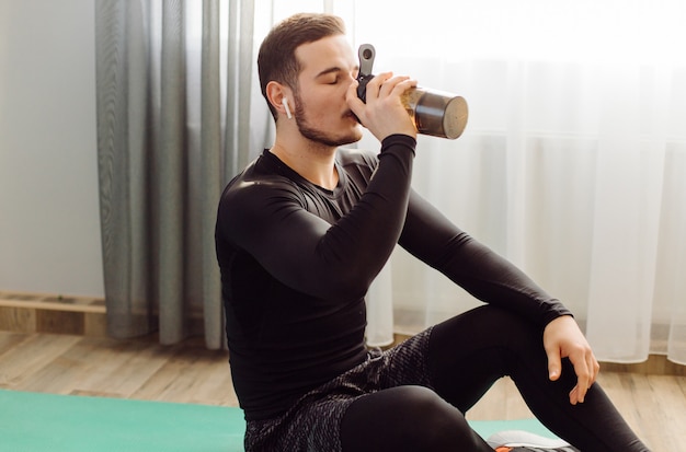 De jonge mens die sport maakt oefent thuis uit