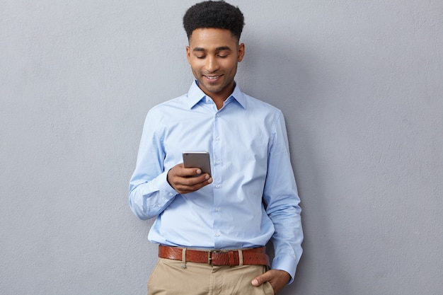 De jonge mens kleedde zich formeel en houdt telefoon vast