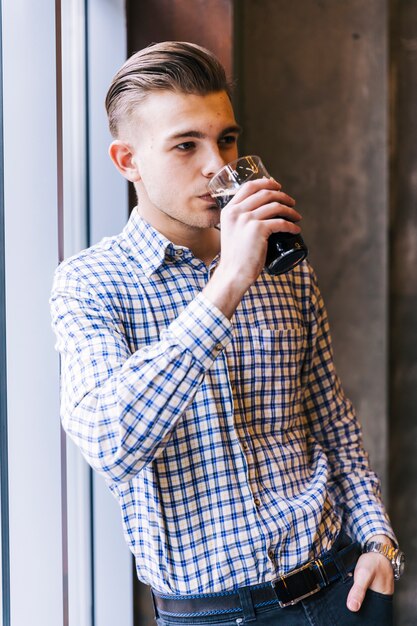 De jonge mens met zijn dient zak in drinkend het bier