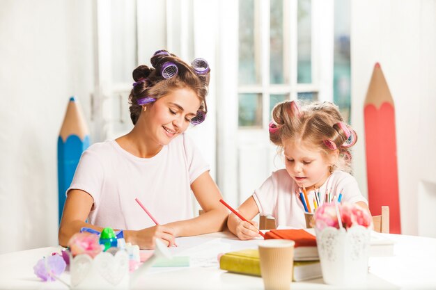 De jonge moeder en haar dochtertje tekenen met potloden thuis
