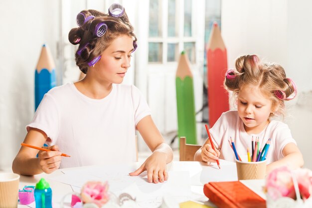 De jonge moeder en haar dochtertje tekenen thuis met potloden