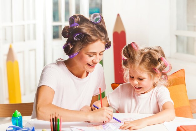 De jonge moeder en haar dochtertje tekenen thuis met potloden