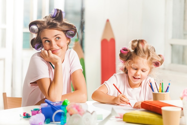 De jonge moeder en haar dochtertje tekenen thuis met potloden