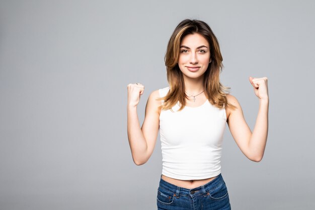 De jonge mooie vrouw toont sterke handen die op grijze muur worden geïsoleerd