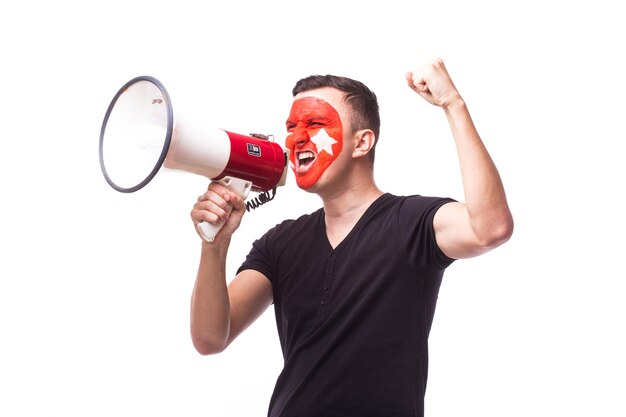 De jonge ventilator van de de mensenvoetbal van Tunesië met megafoon die op witte muur wordt geïsoleerd