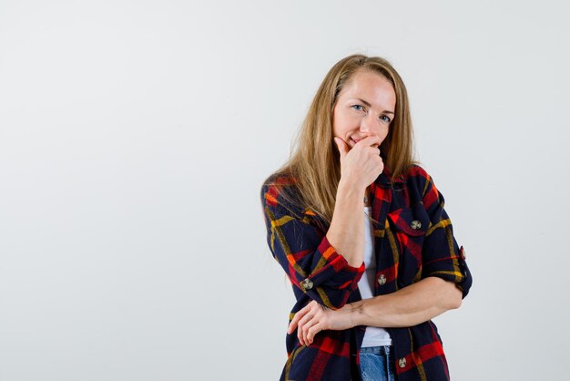 de jonge vrouw denkt door haar hand op de mond op een witte achtergrond te leggen