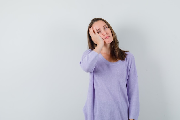 De jonge vrouw die naar haar leunt dient lila blouse in en kijkt verveeld. vooraanzicht. ruimte voor tekst