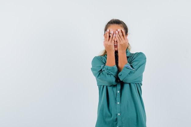 De jonge vrouw die ogen behandelt dient groene blouse in en kijkt moe