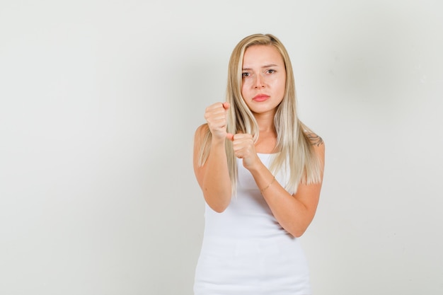 Gratis foto de jonge vrouw die zich in bokser bevindt stelt in hemd en kijkt boos