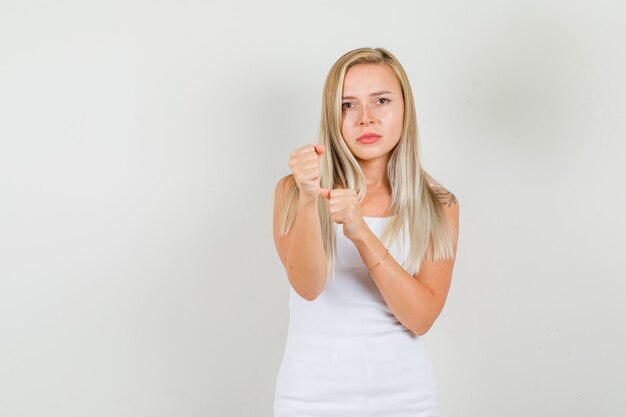 De jonge vrouw die zich in bokser bevindt stelt in hemd en kijkt boos