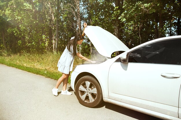 De jonge vrouw gaf de auto pech terwijl ze onderweg was om uit te rusten. Ze probeert de kapotte zelf te repareren of zou moeten liften. Nerveus worden