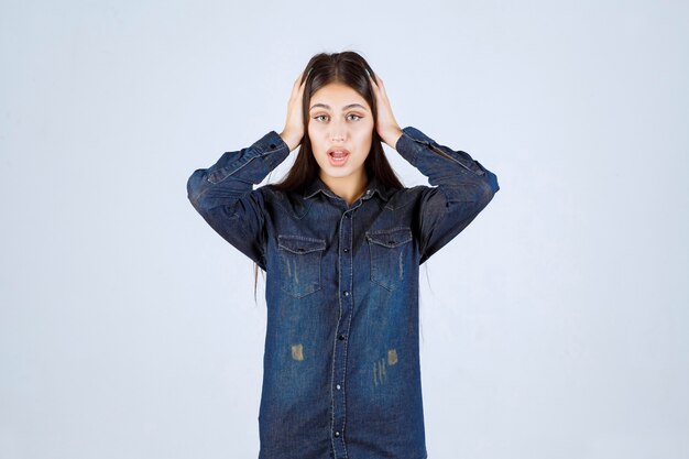 De jonge vrouw in een spijkeroverhemd ziet er bang en bang uit