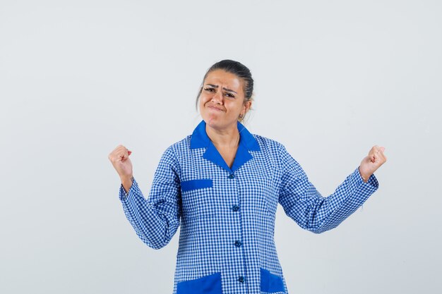 De jonge vrouw in het blauwe overhemd die van de gingangpyjama winnaar tonen stelt en kijkt mooi, vooraanzicht.