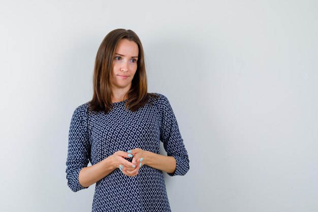 De jonge vrouw kijkt naar rechts door haar gekruiste handen op een witte achtergrond te houden