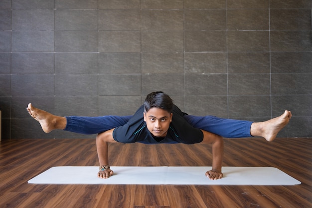 De jonge yogi die firefly doen stelt en in gymnastiek in evenwicht brengt