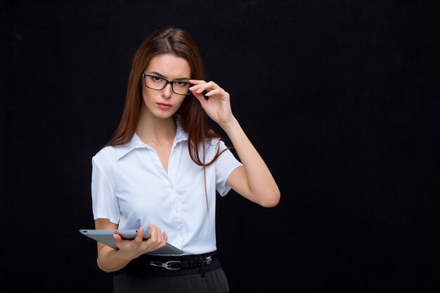 De jonge zakenvrouw met tablet op zwarte achtergrond