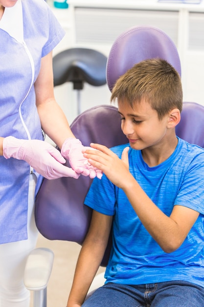 De jongen die pillen van tandarts neemt dient kliniek in