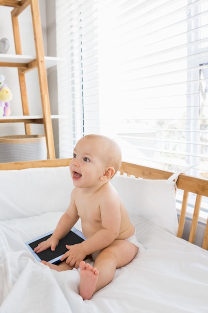 De jongen van de baby het spelen met digitale tablet op een wieg