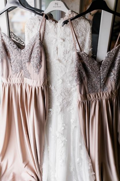 De jurk van de bruid en haar twee bruidsmeisjesjurken hangen aan hangers