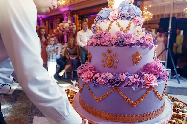 De kelner draagt ​​luxueuze violette verfraaide huwelijkscake