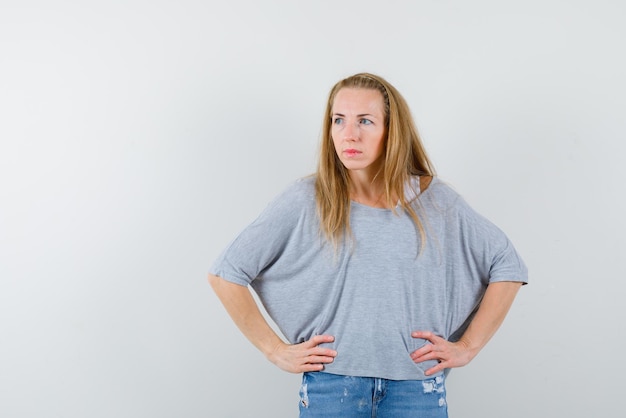 De kijkende linkse vrouw legt handen op de taille op een witte achtergrond