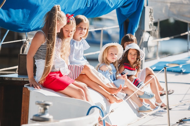 De kinderen aan boord van een zeiljacht. De tiener- of kindmeisjes buiten.