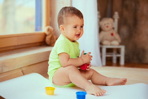 De kleine baby houdt een doos met verven