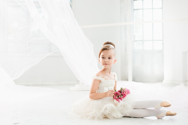 De kleine balerina in witte tutu in de klas op de balletschool