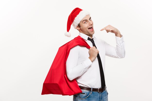 De knappe Bedrijfsmens viert vrolijke Kerstmis die santahoed met de rode grote zak van de Kerstman draagt.