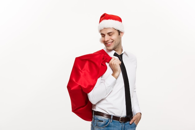 De knappe Bedrijfsmens viert vrolijke Kerstmis die santahoed met de rode grote zak van de Kerstman draagt.