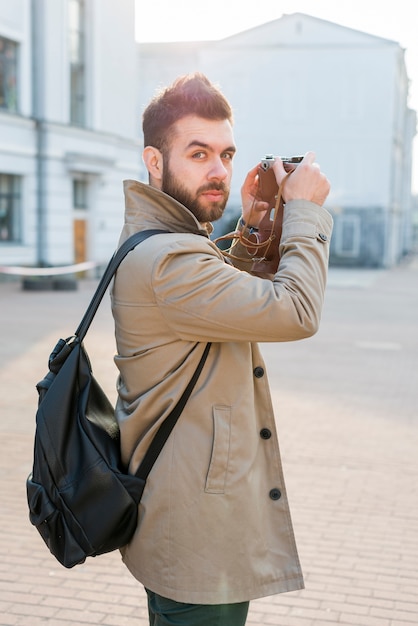 De knappe mannelijke camera van de reizigersholding die ter beschikking camera bekijken