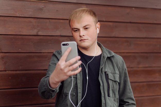 De knappe mens gebruikt openlucht laptop en telefoon op houten muur