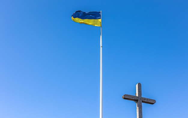 De kruisiging van Jezus Christus en de vlag van Oekraïne tegen de blauwe lucht