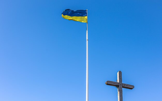 De kruisiging van Jezus Christus en de vlag van Oekraïne tegen de blauwe lucht