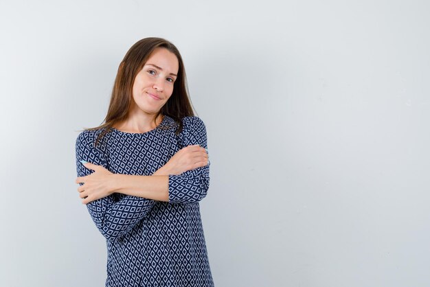 De lachende vrouw kruist haar armen op een witte achtergrond